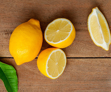 lemon and cut lemons on wooden board with leaf