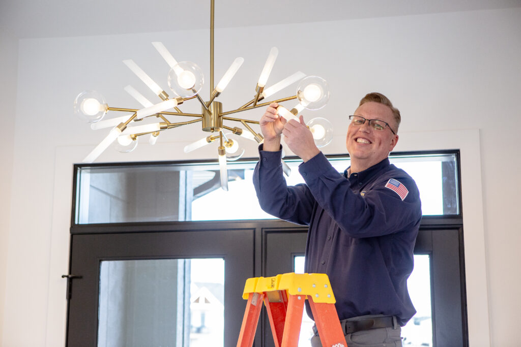 Lighting Services Iowa - Electrician in Blue Shirt Repairs Light